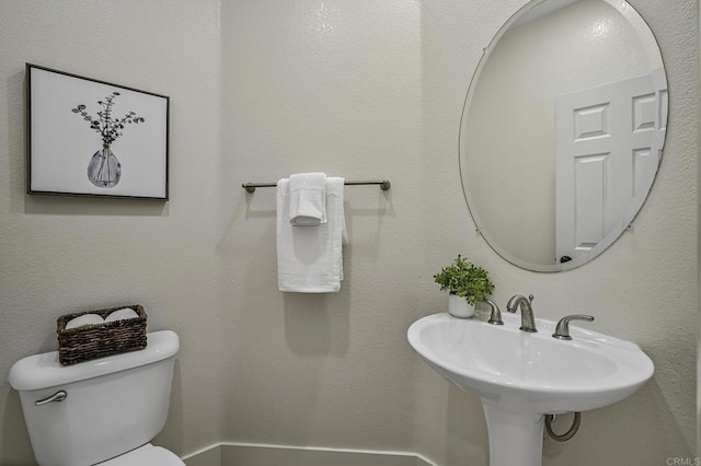 half bathroom featuring toilet and a sink