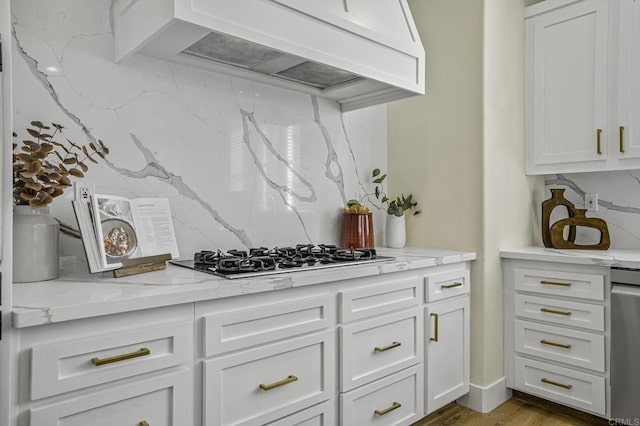 kitchen with custom exhaust hood, white cabinets, tasteful backsplash, and gas cooktop