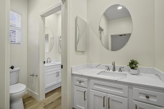 bathroom with toilet, wood finished floors, and vanity