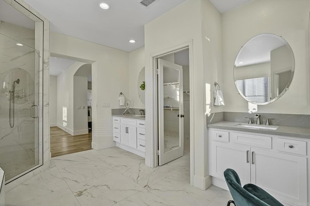 full bathroom featuring a marble finish shower, marble finish floor, two vanities, and a sink