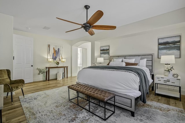 bedroom featuring arched walkways, baseboards, and wood finished floors