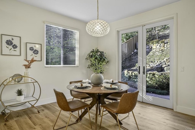 dining room with french doors, baseboards, and light wood-style flooring