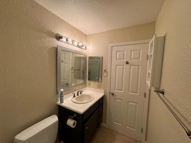 bathroom with tile patterned floors, a textured ceiling, toilet, and vanity