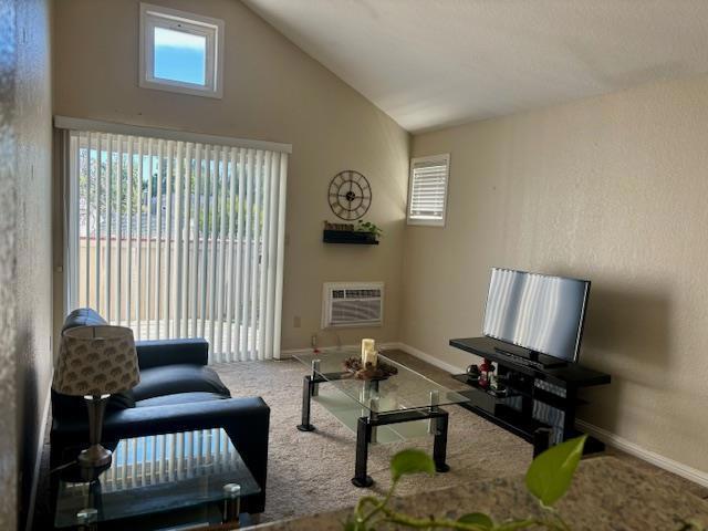 living room with carpet floors, an AC wall unit, and lofted ceiling