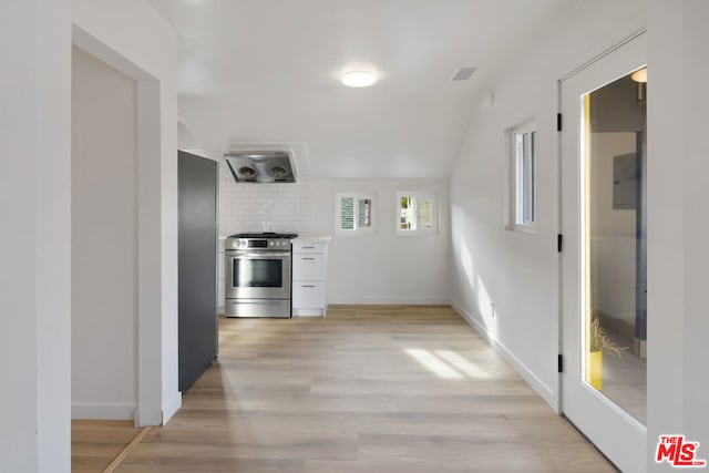 corridor with light hardwood / wood-style floors and lofted ceiling