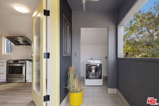 clothes washing area featuring washer / dryer and light tile patterned floors