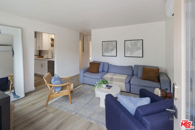 living room with light hardwood / wood-style flooring, a wall mounted AC, and sink