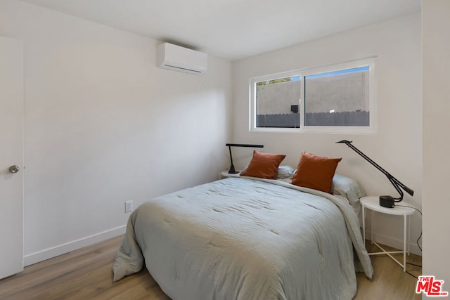 bedroom with a wall unit AC and light hardwood / wood-style flooring