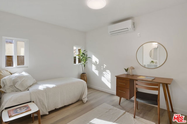 bedroom with a wall mounted air conditioner and light wood-type flooring