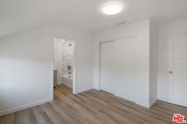 unfurnished bedroom with hardwood / wood-style floors, a closet, and ensuite bath