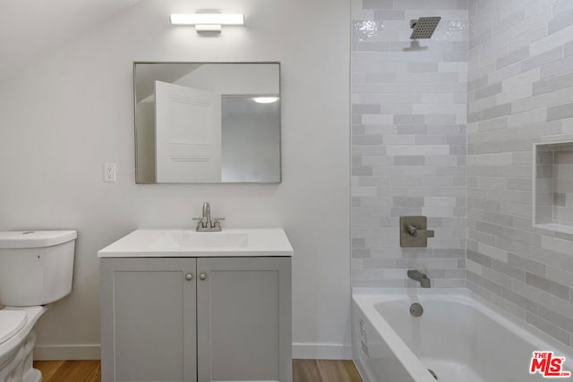 full bathroom with vanity, toilet, wood-type flooring, and tiled shower / bath