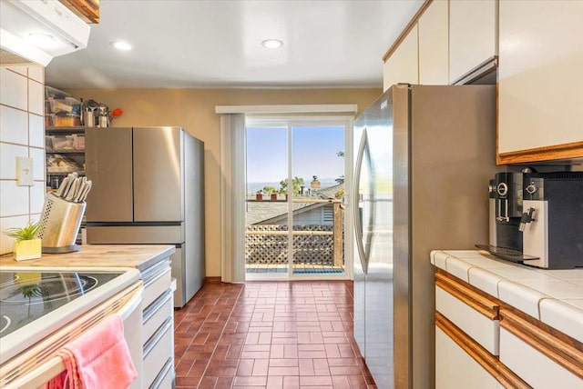 kitchen featuring white cabinets, tile countertops, and stainless steel refrigerator