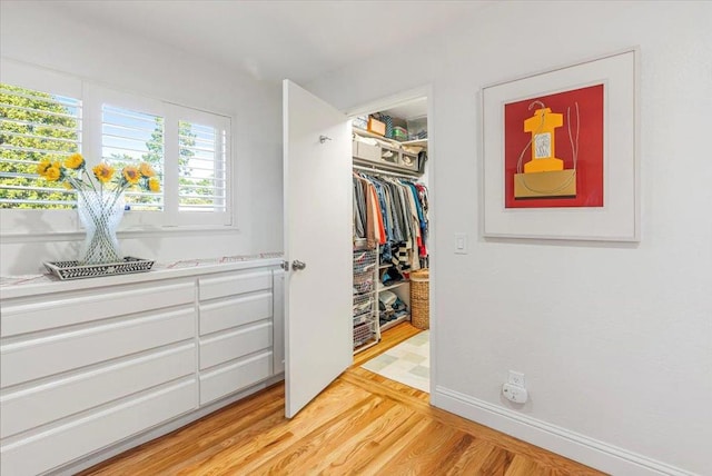 walk in closet with light hardwood / wood-style flooring