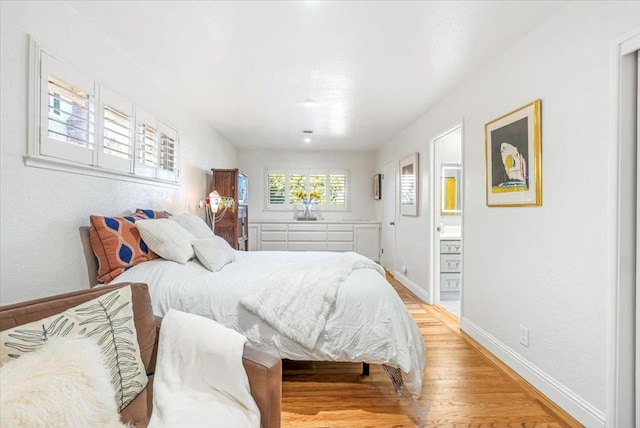 bedroom with light wood-type flooring and ensuite bathroom