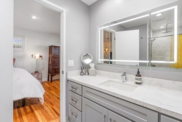 bathroom with wood-type flooring, vanity, and a tile shower