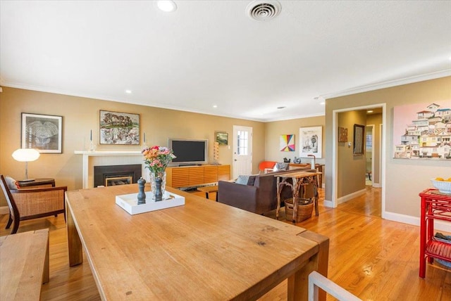 dining room with ornamental molding and light hardwood / wood-style floors