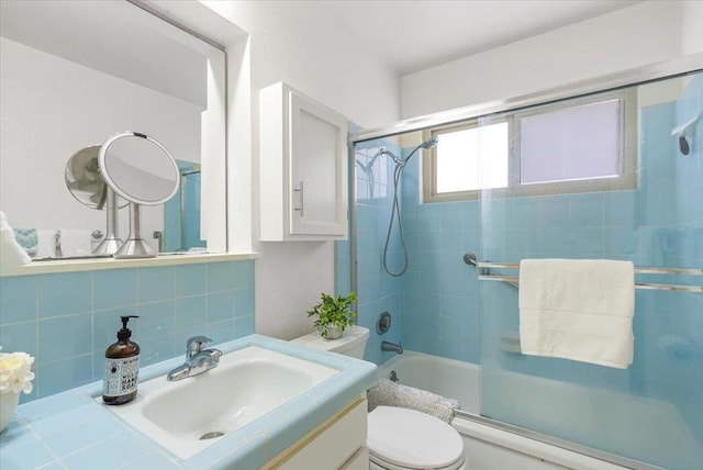 full bathroom featuring backsplash, shower / bath combination with glass door, vanity, and toilet