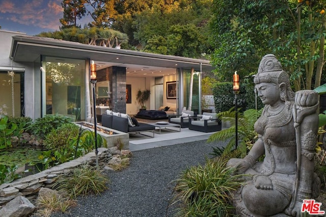 back house at dusk featuring a patio area and outdoor lounge area