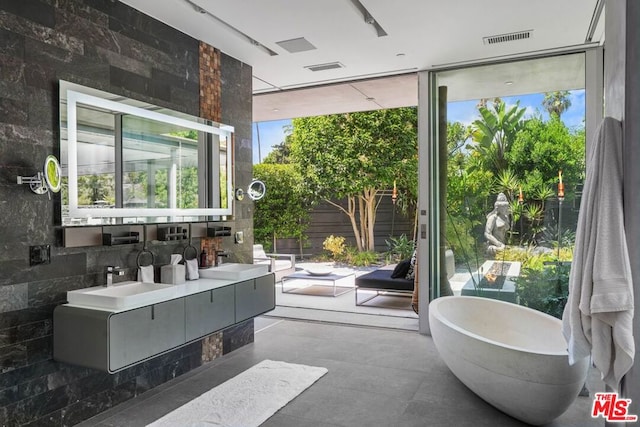 bathroom featuring vanity, a washtub, and a wall of windows