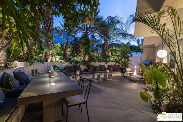 patio terrace at dusk with an outdoor living space with a fire pit