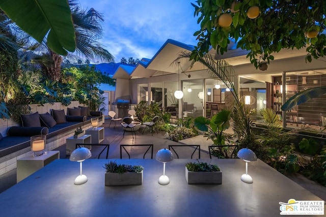 patio terrace at dusk with outdoor lounge area and grilling area