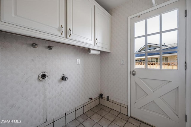 washroom with plenty of natural light, hookup for a gas dryer, light tile patterned floors, and cabinets