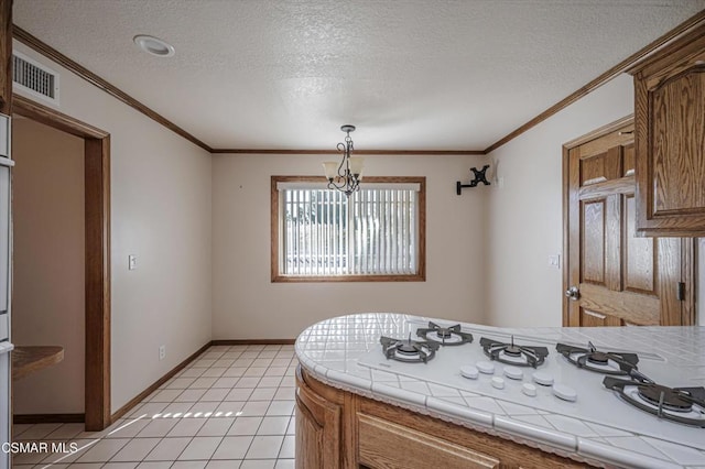 kitchen with a textured ceiling, tile counters, white gas cooktop, light tile patterned flooring, and ornamental molding