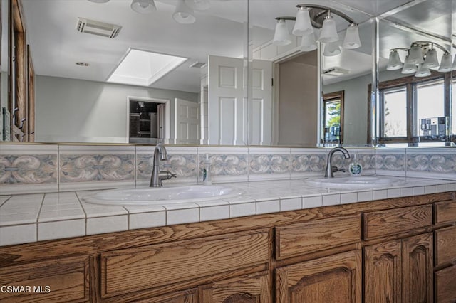 bathroom featuring a skylight, backsplash, and vanity