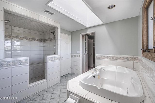 bathroom with shower with separate bathtub, tile patterned flooring, and tile walls