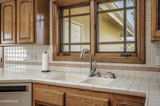 kitchen with sink, tile counters, decorative backsplash, and dishwasher