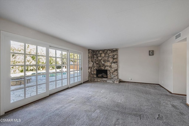 unfurnished living room featuring a stone fireplace and carpet floors