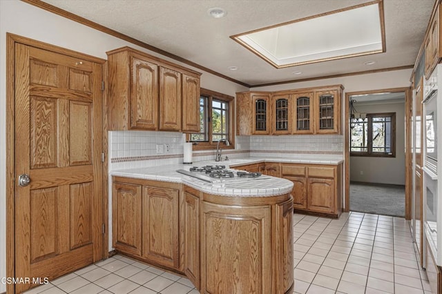 kitchen featuring decorative backsplash, stainless steel gas cooktop, crown molding, and kitchen peninsula