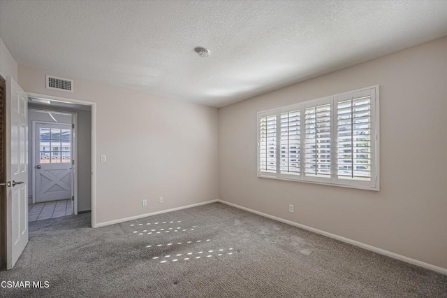 carpeted spare room with a textured ceiling