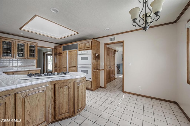 kitchen with white appliances, tile counters, a notable chandelier, decorative light fixtures, and tasteful backsplash