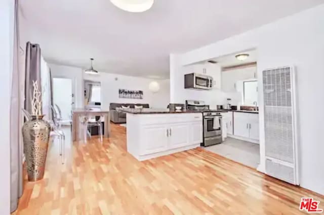 kitchen featuring hanging light fixtures, kitchen peninsula, light hardwood / wood-style flooring, appliances with stainless steel finishes, and white cabinetry