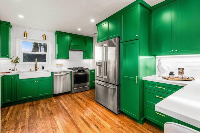 kitchen with custom exhaust hood, hardwood / wood-style floors, stainless steel appliances, green cabinets, and sink