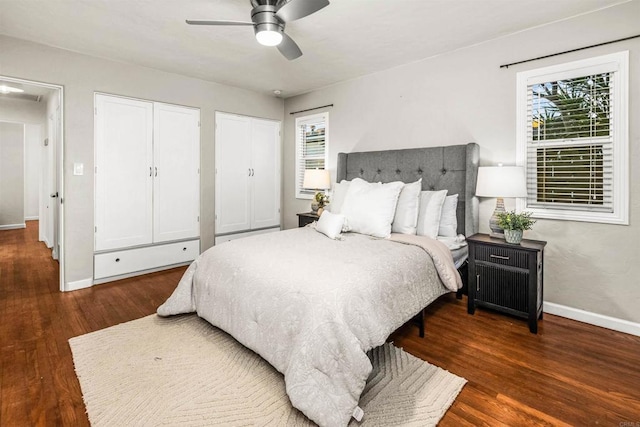 bedroom with dark hardwood / wood-style flooring, two closets, and ceiling fan