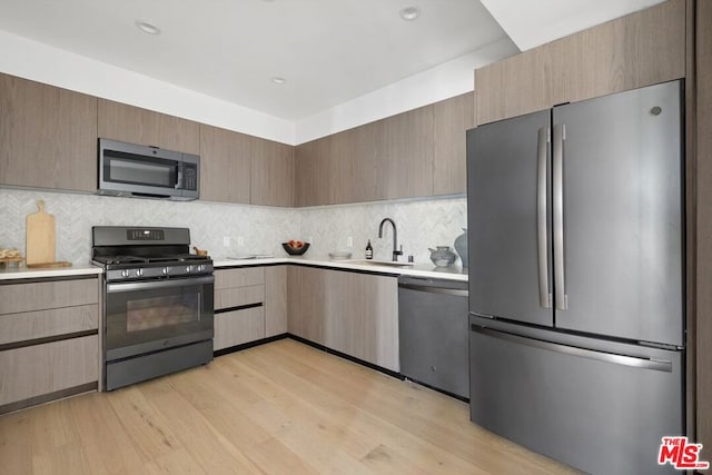 kitchen featuring backsplash, stainless steel appliances, light hardwood / wood-style flooring, and sink