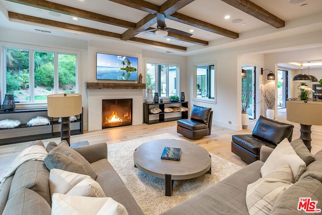 living room featuring ceiling fan, light hardwood / wood-style floors, beam ceiling, and a fireplace