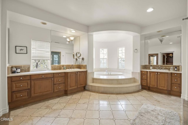 bathroom featuring tasteful backsplash, vanity, and a relaxing tiled tub