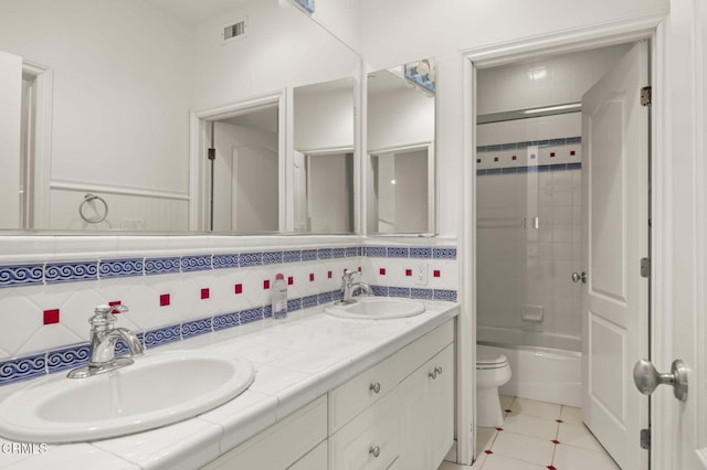 full bathroom featuring toilet, tiled shower / bath, vanity, tile patterned flooring, and backsplash