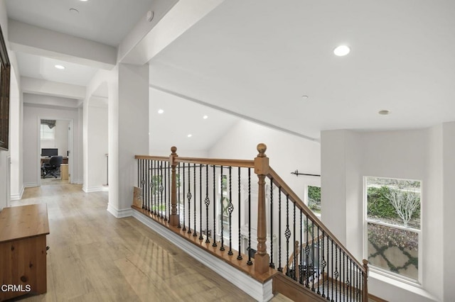 corridor with beam ceiling and light hardwood / wood-style floors