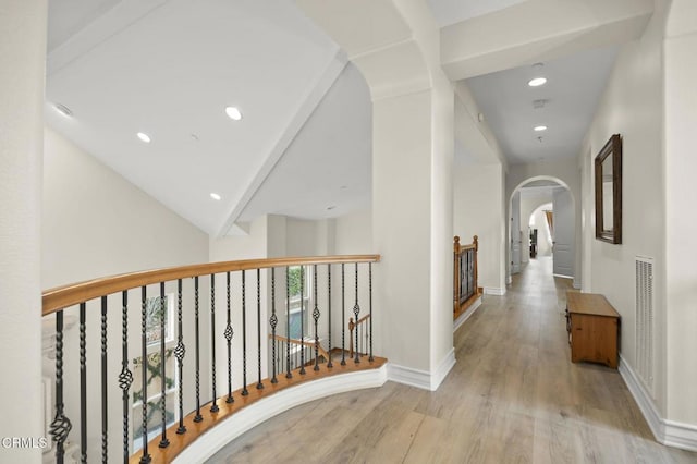 corridor with light hardwood / wood-style floors and beamed ceiling