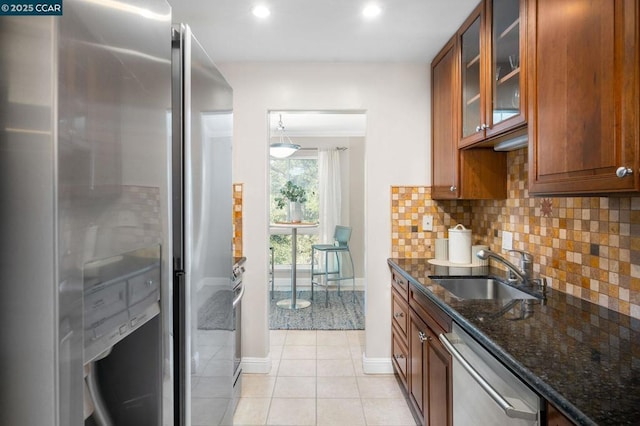 kitchen featuring sink, dark stone countertops, light tile patterned floors, appliances with stainless steel finishes, and decorative light fixtures