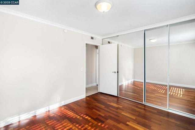 unfurnished bedroom with crown molding, a closet, and dark hardwood / wood-style floors