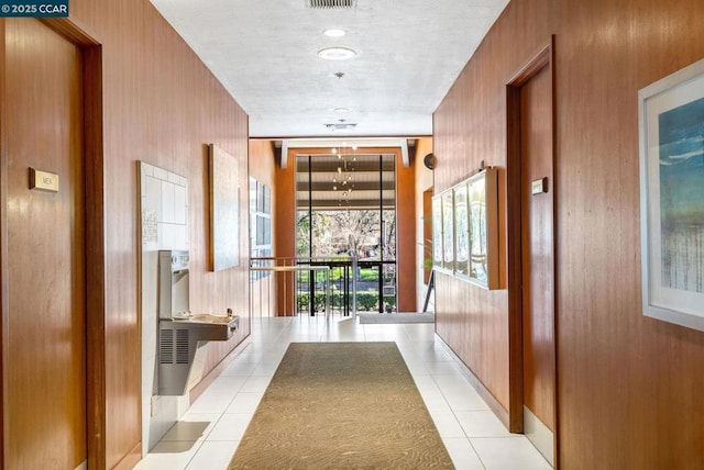 hallway with light tile patterned floors and wooden walls