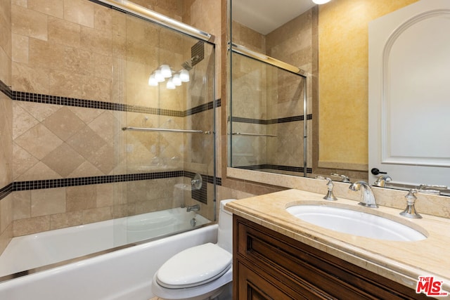 full bathroom featuring toilet, vanity, and combined bath / shower with glass door