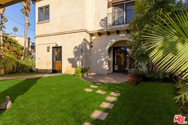 back of house with french doors, a balcony, and a lawn