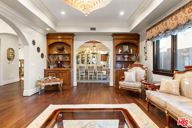 living room featuring ornamental molding, a tray ceiling, an inviting chandelier, and dark wood-type flooring