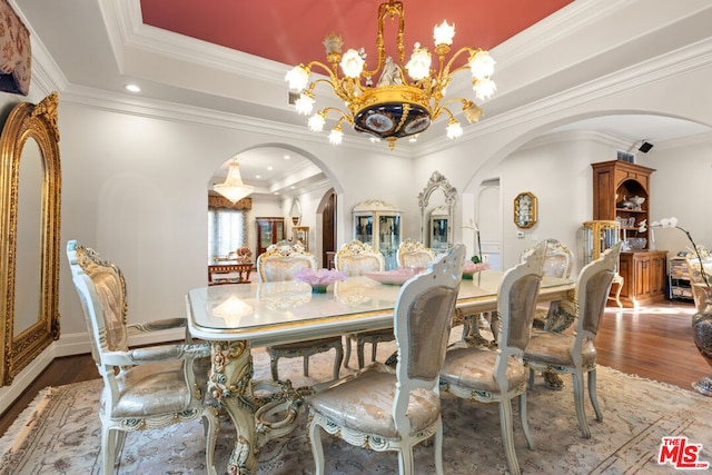 dining room with hardwood / wood-style flooring, ornamental molding, a tray ceiling, and a chandelier